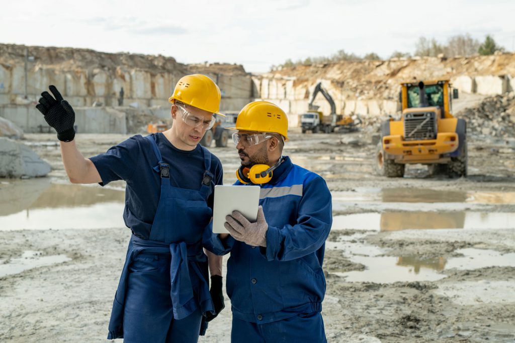 Two mining workers help locate a piece of equipment using the IoT software on their tablet.