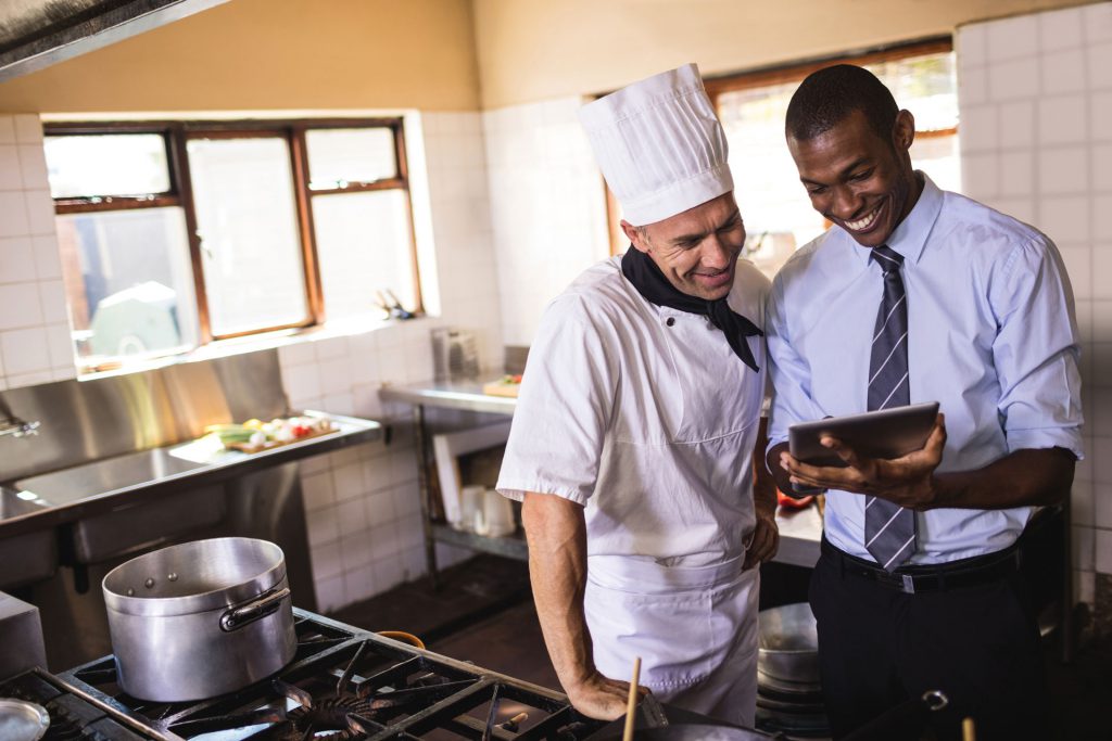 A chef and his manager check the inventory of their cooler remotely using IoT.