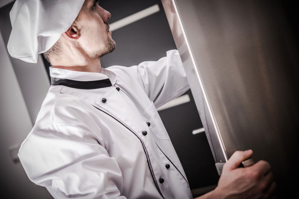 A chef removes ingredients from a refrigerator that is monitored by IoT sensors.