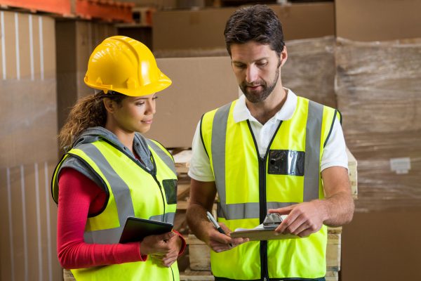 Two warehouse workers discuss the location of a pallet being tracked by IoT.