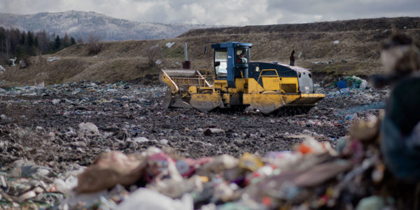 Large equipment moves debris in a waste management facility while being tracked remotely using an IoT asset tracker.