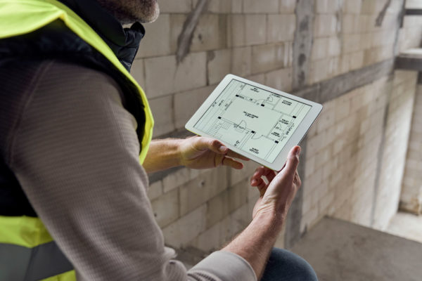 A construction worker viewing a floorplan that shows the location of IoT plumbing montioring devices in a new construction. location.