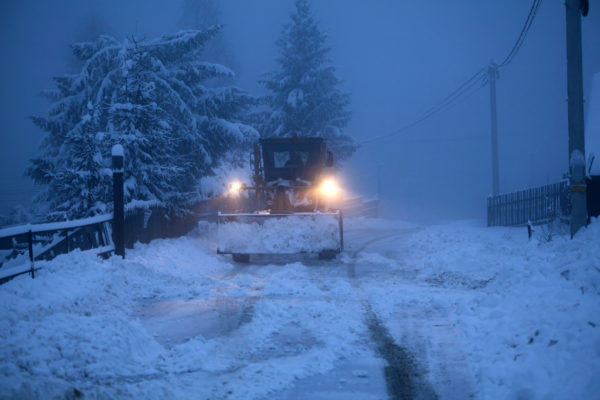 A snowplow cleaning a road that has been equipped with an IoT temperature and humidity sensor.