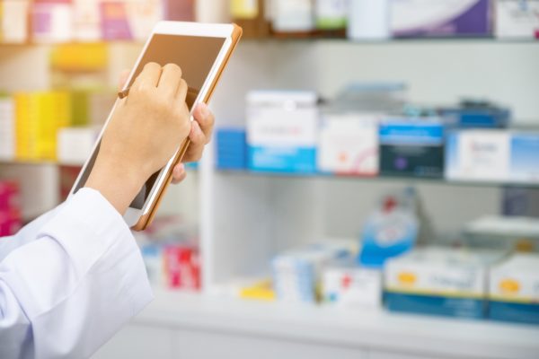 A pharmacist using a tablet to monitor the IoT enabled devices in the pharmacy.