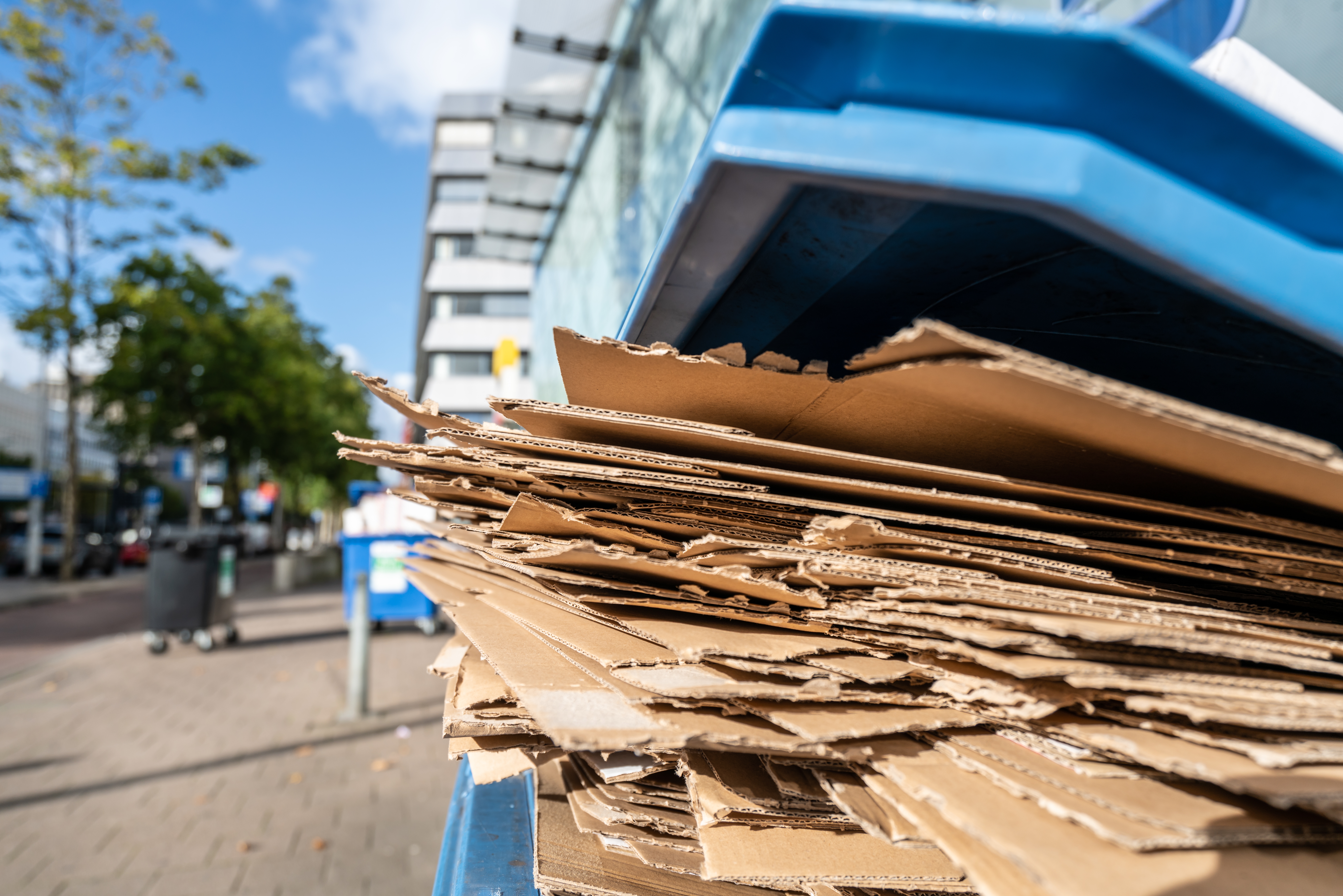 A pile of cardboard sticking out of an IoT monitored recycling bin.