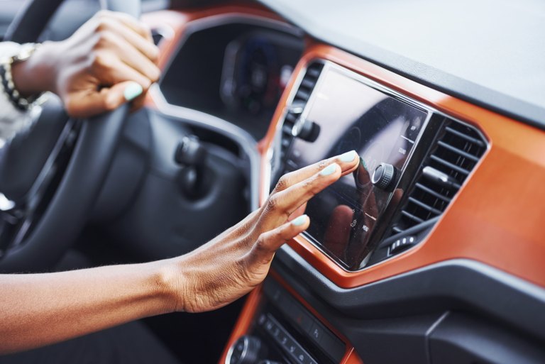A woman touches display in a car that is powered by IoT.